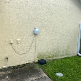 Exterior of Cape Coral home before house washing, with visible grime, algae streaks, and a faded appearance.