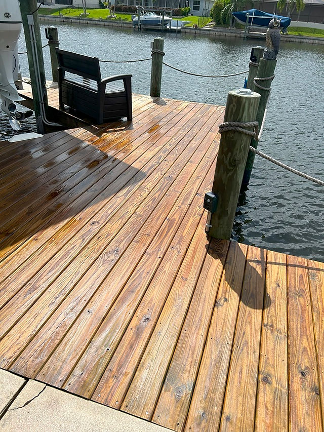 A restored wooden dock in Cape Coral with vibrant, warm wood tones after cleaning and refinishing by AAA Pressure Washing.