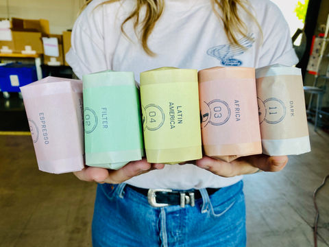 A person holding bags of cofee