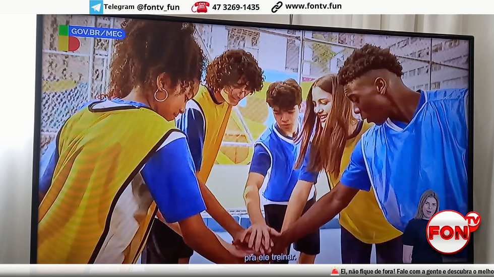 Um grupo de crianças em trajes esportivos reunidos com as mãos juntas, em uma tela de TV.