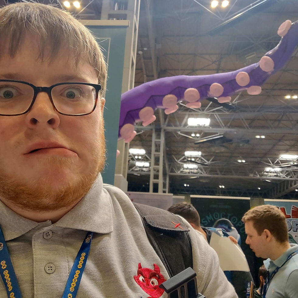 in the foreground, Gregor is pulling a scared face, in the background, Stone Sword Games' Cosmoctopus tentacle extends above NEC Hall 1