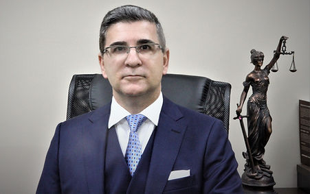 Dr. Keops sentado na sua cadeira. Ao seu lado está a estátua da justiça.