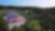 A drone image of the Nest building. You can see the full building, cabins and the south field in the background and a bit of the lake.