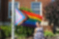 person smiling with a large pride flag
