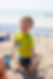A camper smiles at the camera while playing in the sand on the beach.