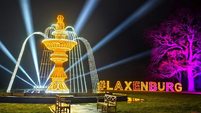 A fountain covered in small gold and silver pea lights with benches in front of it and LAXENBURG written in lights to the right hand side