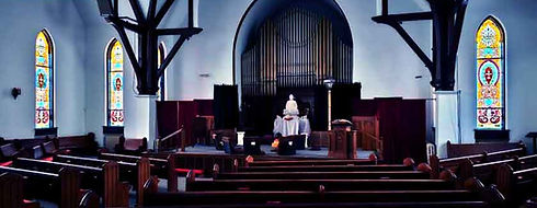 The ornate sanctuary of Father John's Church in Bryan, Ohio, featuring stained glass windows and historic wooden pews.