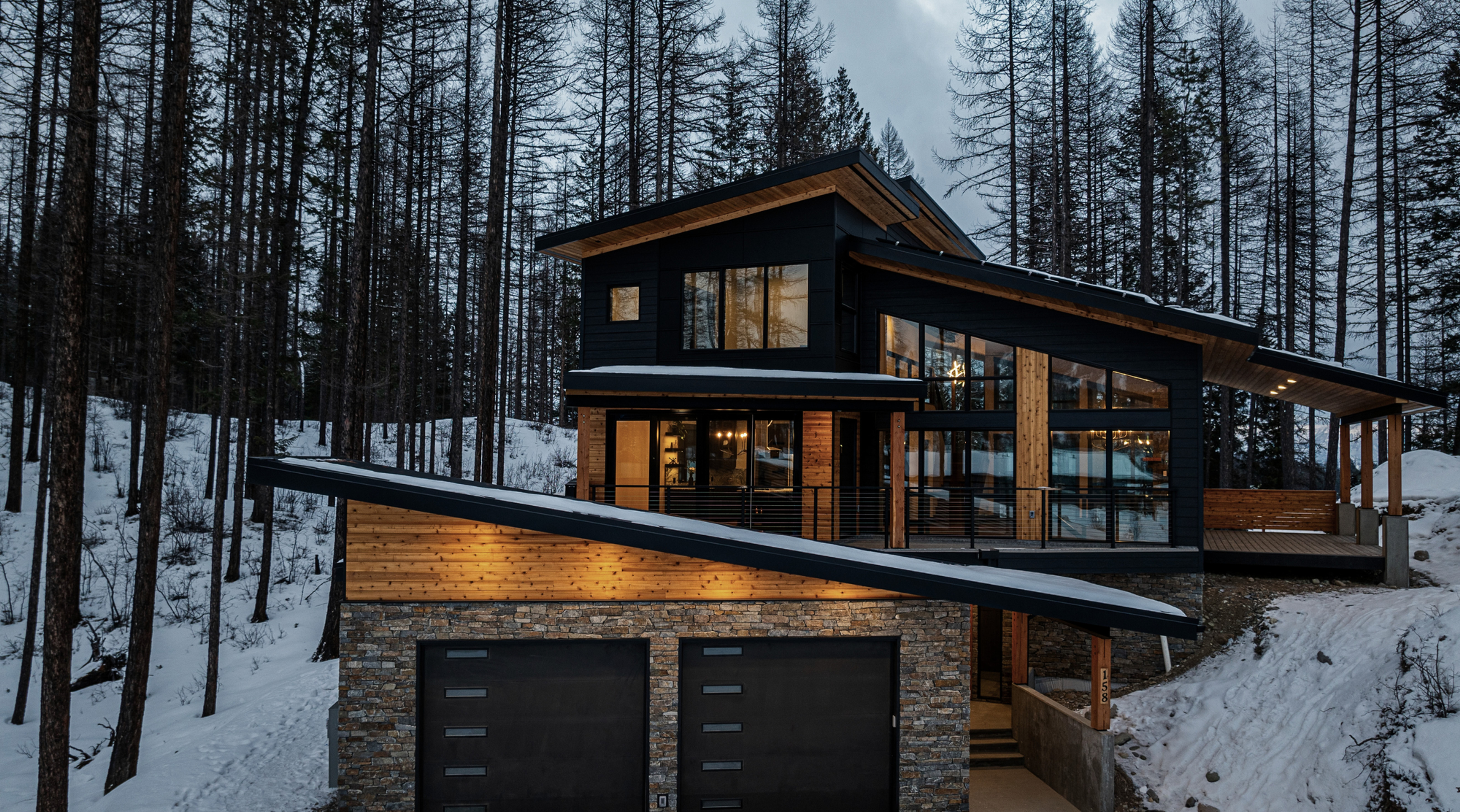 Modern custom home built into a snowy, sloped forest site in the East Kootenays.