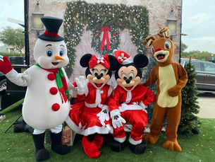 Snowman mascot with Minnie and Minnie Mouse mascots dressed as Santa and Mrs. Clause and Rudolph the Red Nose Reindeer mascot taking a group photo.