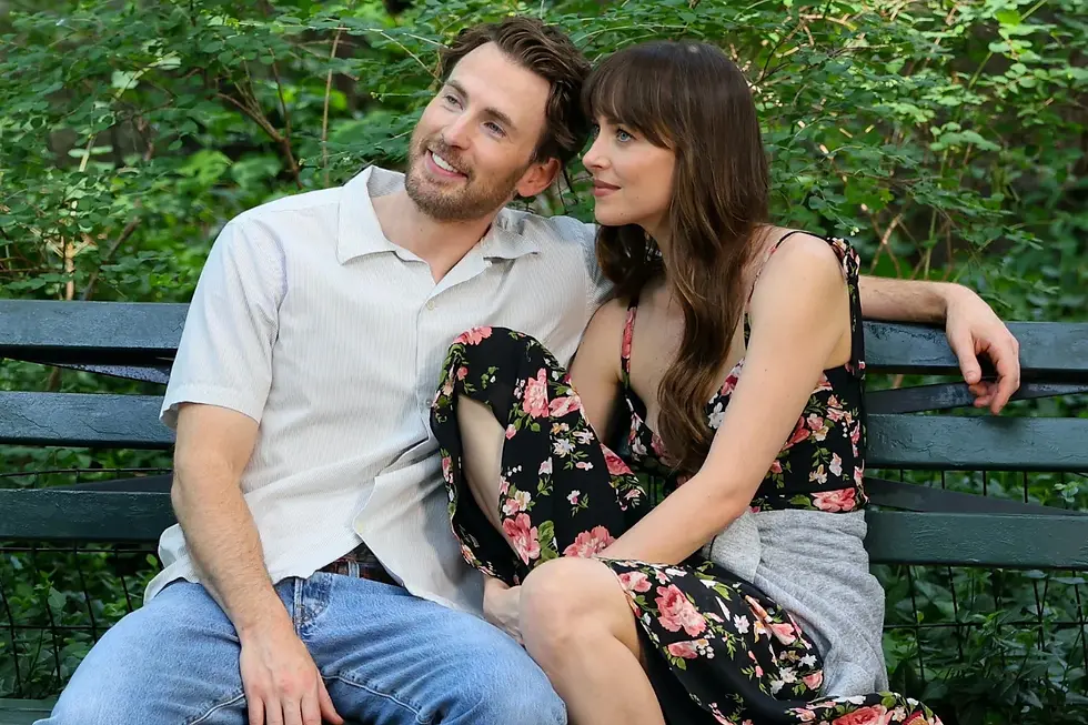 Chris Evans and Dakota Johnson sitting on a public chair in the park.