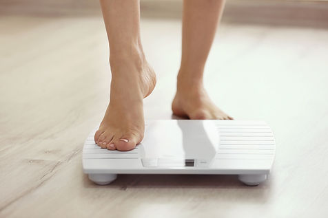 woman standing on bathroom scales worrying about her weight and diet