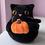 Thumbnail: Black cat plush toy holding an orange pumpkin