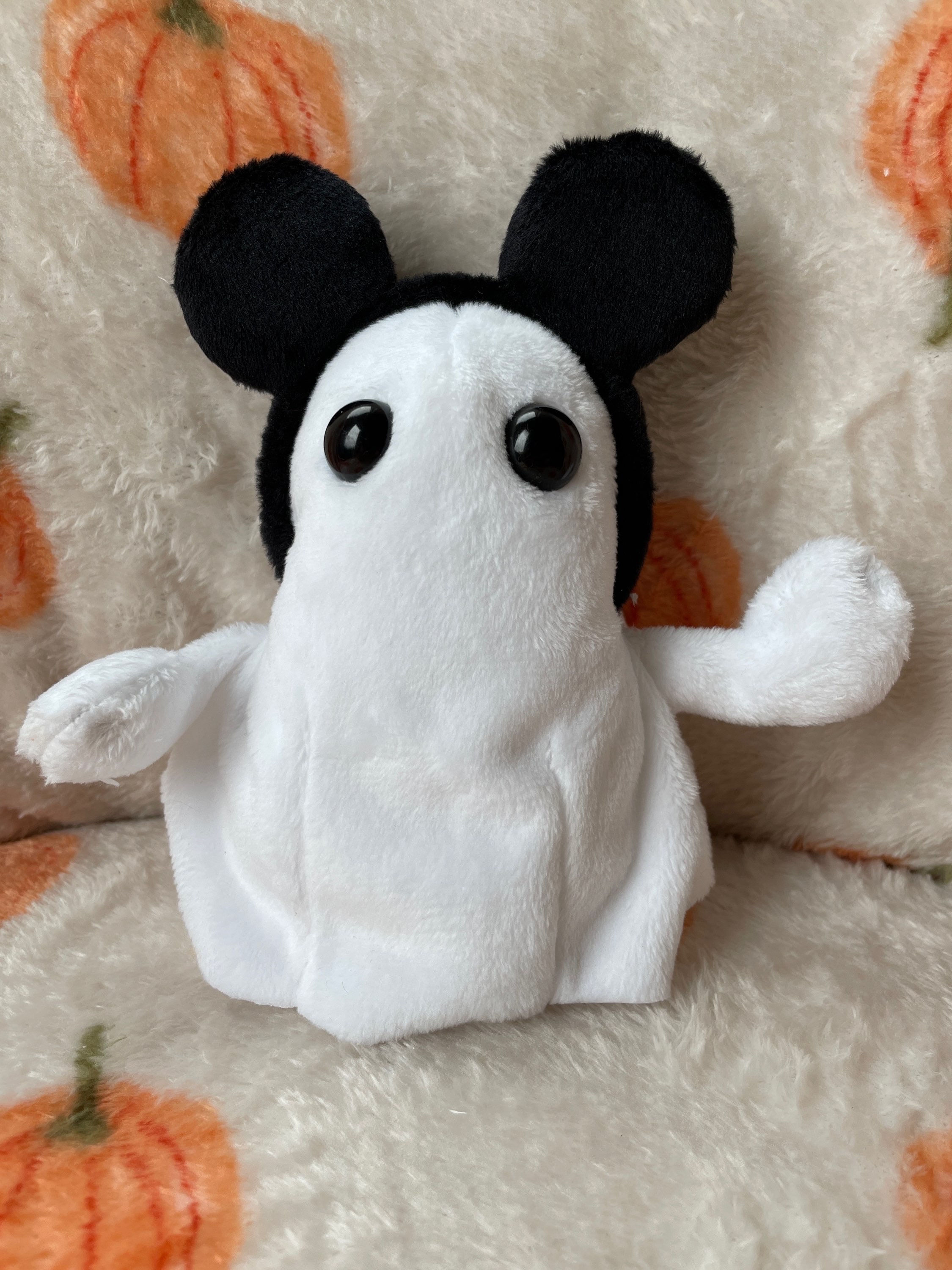 Ghost plush with black mickey mouse ears on its head.