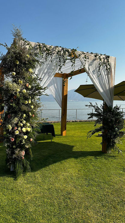 Jupa floral con follaje y rosas claras frente al lago, diseño ceremonial para boda judia, creado por La Petite Fleur Floral Design. Escenario simbólico y elegante para una unión sagrada