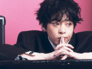 xiumin, membro do exo, com cabelos pretos, terno preto e fundo rosa. imagem de divulgação de seu album solo "interview x"