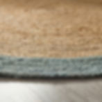 Thumbnail: Close-up of a round jute rug with a blue decorative border on a wooden floor.
