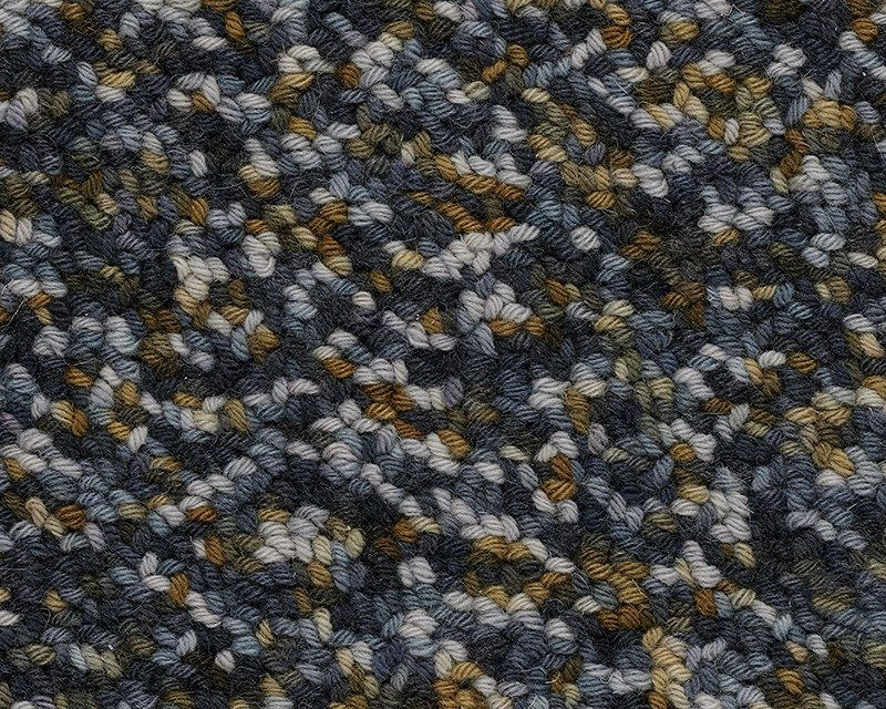 Thumbnail: Close-up of a wool rug with a textured pattern of dark blue, gray, white, and tan yarns.