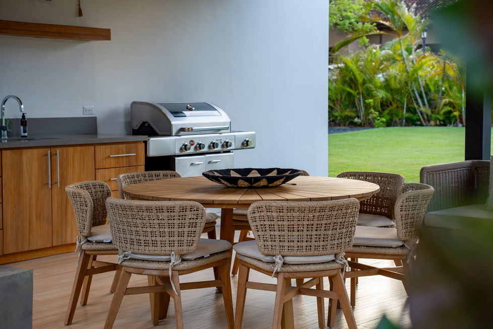 Outdoor dining area with round table and barbecue grill.
