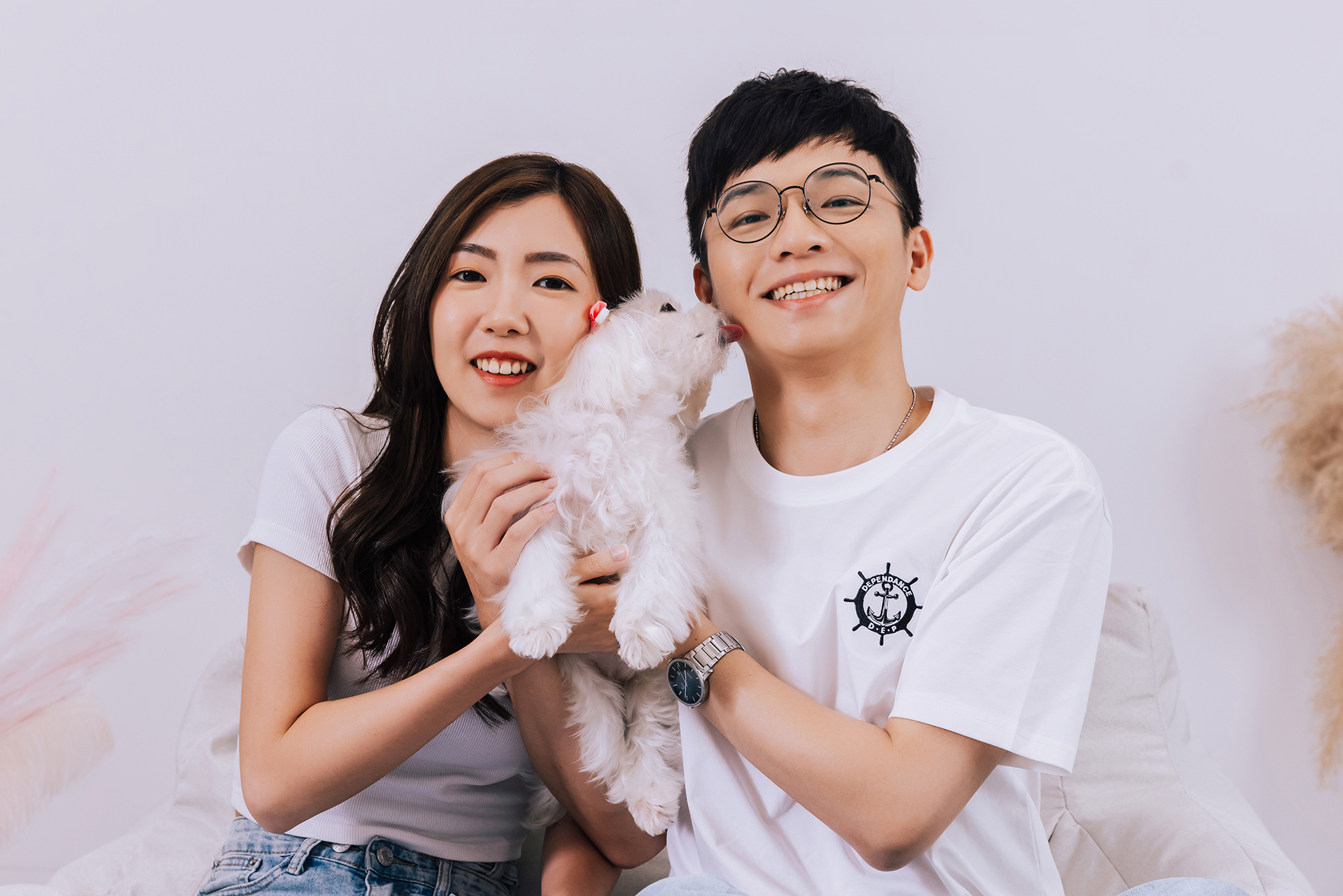 情侶抱著白色貴賓犬合照，狗狗親吻男生臉頰