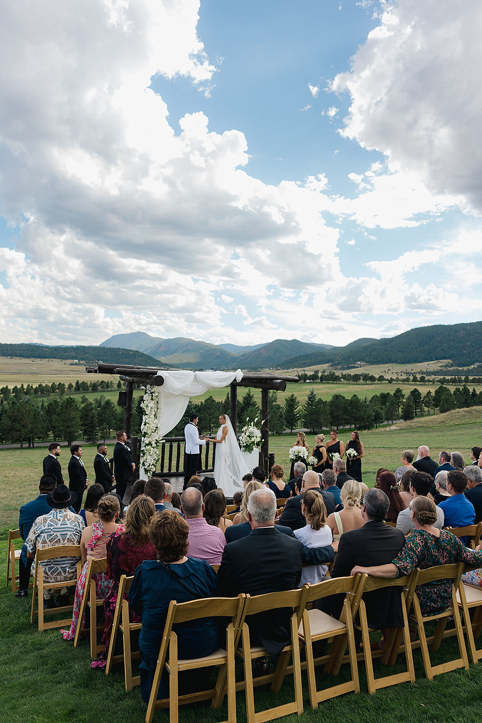 Kennedy and Antonio exchanging vows during an outdoor wedding ceremony overlooking the mountains at Spruce Mountain Ranch.