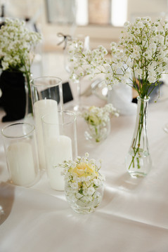 Elegant white floral wedding centerpiece with baby's breath and candles at The Oaks at Plum Creek reception.