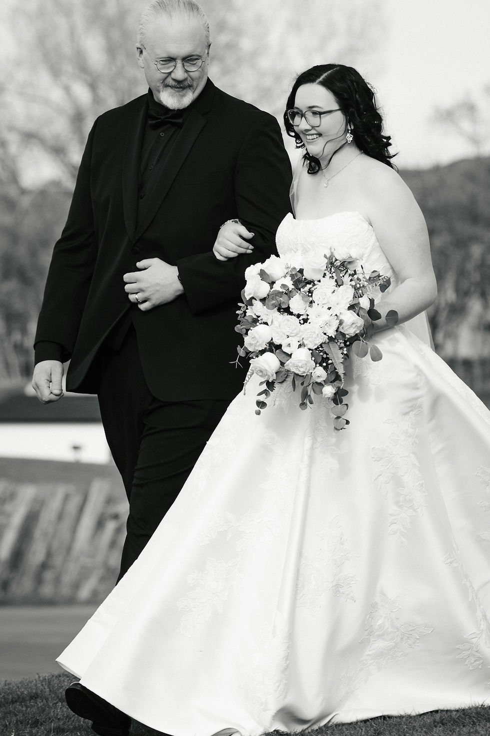 Bride walking down the aisle with her father during an outdoor wedding ceremony at The Oaks at Plum Creek.