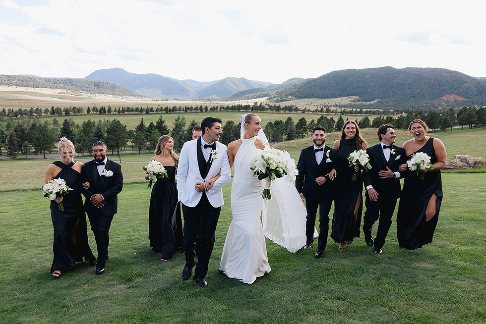 Kennedy and Antonio walking with their wedding party against a scenic Colorado mountain backdrop at Spruce Mountain Ranch.