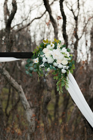 White floral arrangement and greenery decorating the ceremony arbor at The Oaks at Plum Creek.
