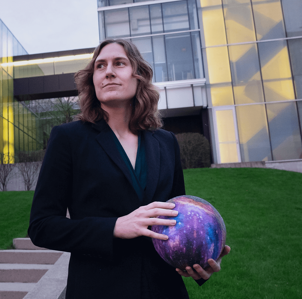 Katie Mack standing in front of the Perimeter Institute for Theoretical Physics, holding a ball covered in a galaxy pattern