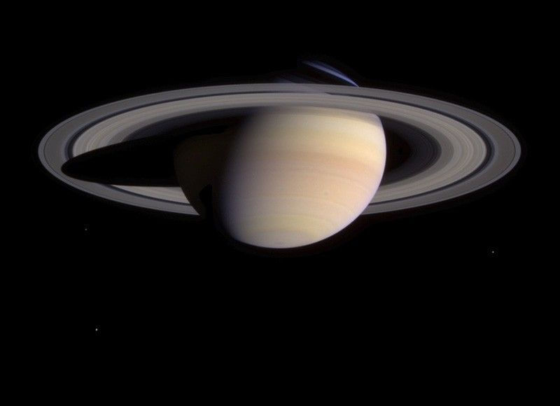 Saturn with prominent rings against a black space background. The planet is beige with subtle stripes, creating a serene, majestic mood.
