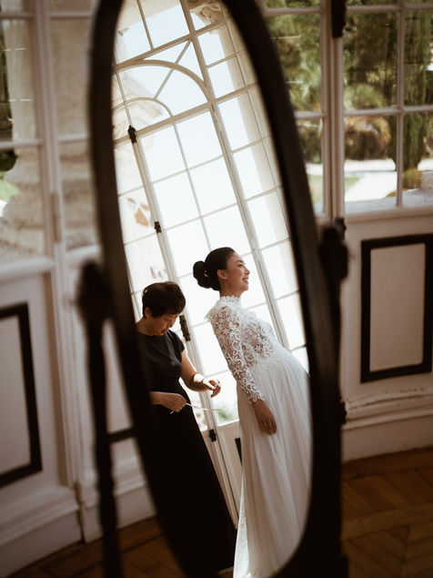 photo dans un miroir de la mariée avec sa mere qui l'habille