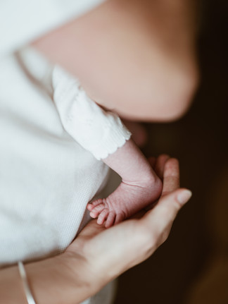 photo d'une maman qui tient le pied de son bébé dans sa main