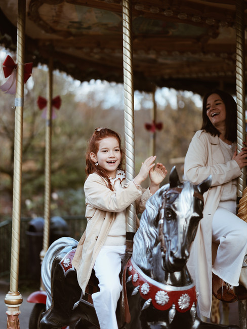 Petite fille qui s'amuse sur le manège-carrousel du jardin public durant une séance photo famille