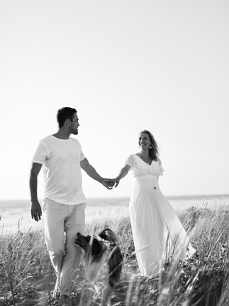 photo en boir et blanc d'un couple qui marche en se tenant la main, leur chien a leurs côtés
