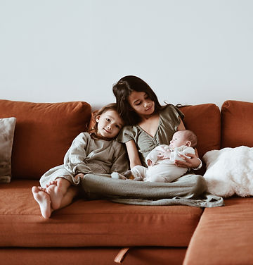 Photographie de soeurs qui portent leur petit frère nouveau-né