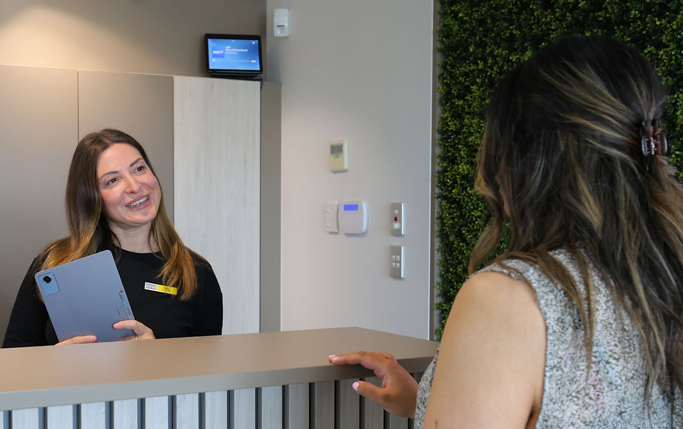 Female receptionist speaking to a female patient at the reception desk.