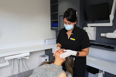 Female dentist performing a jaw muscle test on a happy female patient.