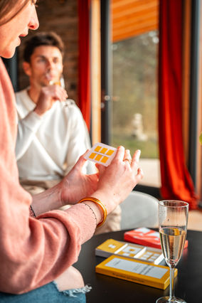 Homme tient carte jaune, autre personne derrière. Cocoon Wood, logements Insolites Savoie.