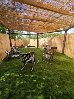 Un espace extérieur avec des chaises et des transats sur une pelouse verte.