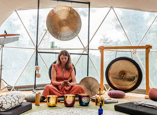 Femme jouant instruments musicaux avec des gongs, des bols chantants, et des bougies.