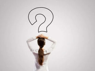 Frau schaut auf ein Fragezeichen an einer grauen Wand.