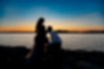 Maternity photo of pregnant woman and partner by the water.
