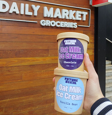 Hand holding two Future Swirl ice cream tubs in front of the Daily Market Kambri in Canberrajpg