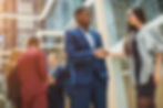 Business professionals shaking hands at a networking event, exemplifying the principles of business ethics and social well-being.