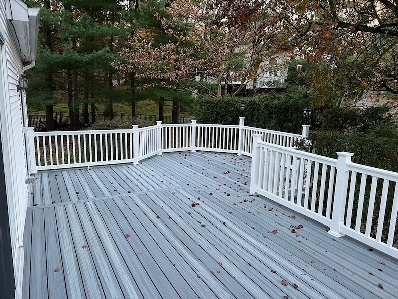 Elegant composite decking with white railing and autumn leaves in a New Jersey backyard.