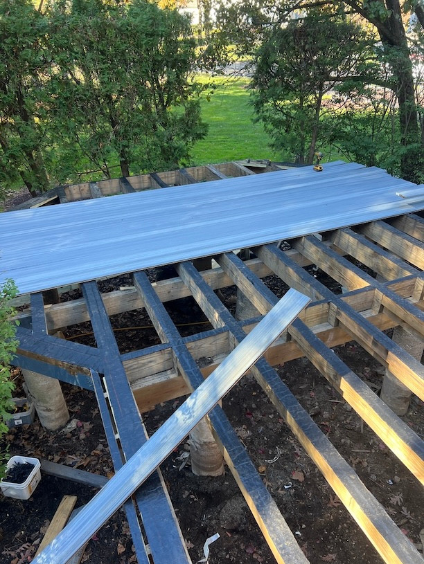 Overhead view of composite deck framework installation among trees, showcasing the beginning stages.