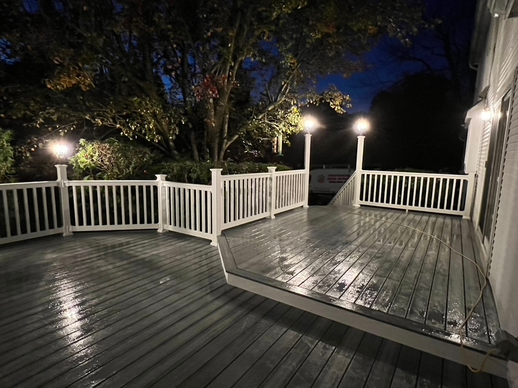 Nighttime view of a well-lit deck built by Util Construction in New Jersey, showcasing outdoor lighting and composite decking materials.