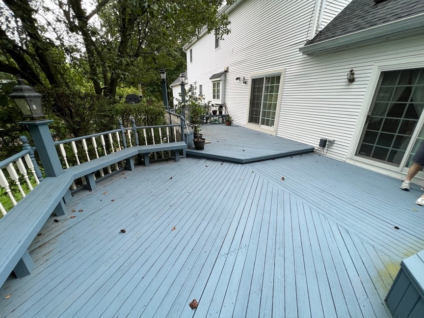 Residential blue painted wooden deck with white railings and outdoor seating.