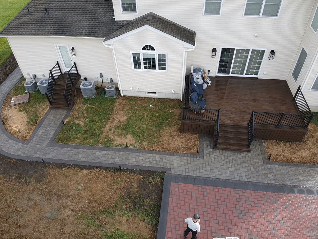 Aerial view of a modern composite deck by Util Construction with outdoor furniture and paved walkway in New Jersey.