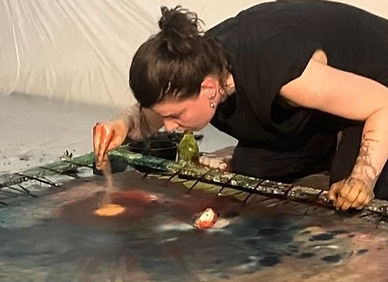 female artist decorating and showing how to create abstract art and she puts yellow soil on a large canvas making a unique and surreal painting for living
